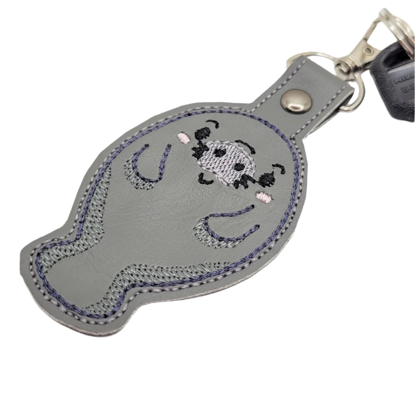 Embroidered vinyl keychain featuring a chibi manatee with a smiling face, attached to a set of keys