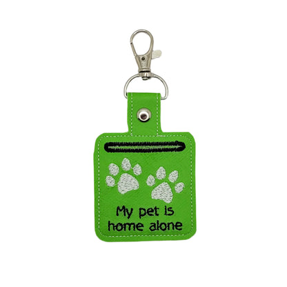 Green keychain with paw prints and text on a gray background