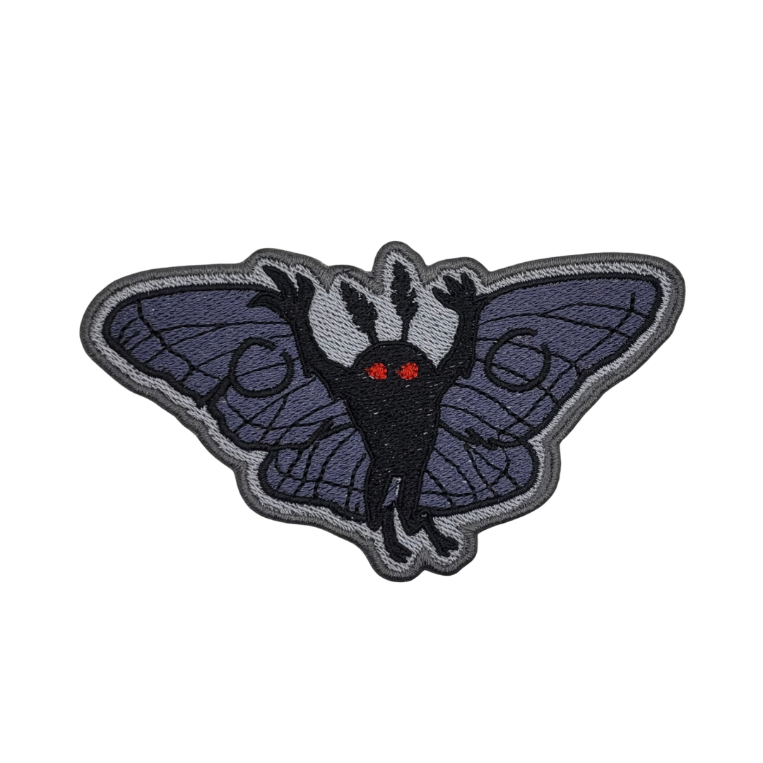 A patch featuring an embroidered image of a moth with red eyes and outlined wings.