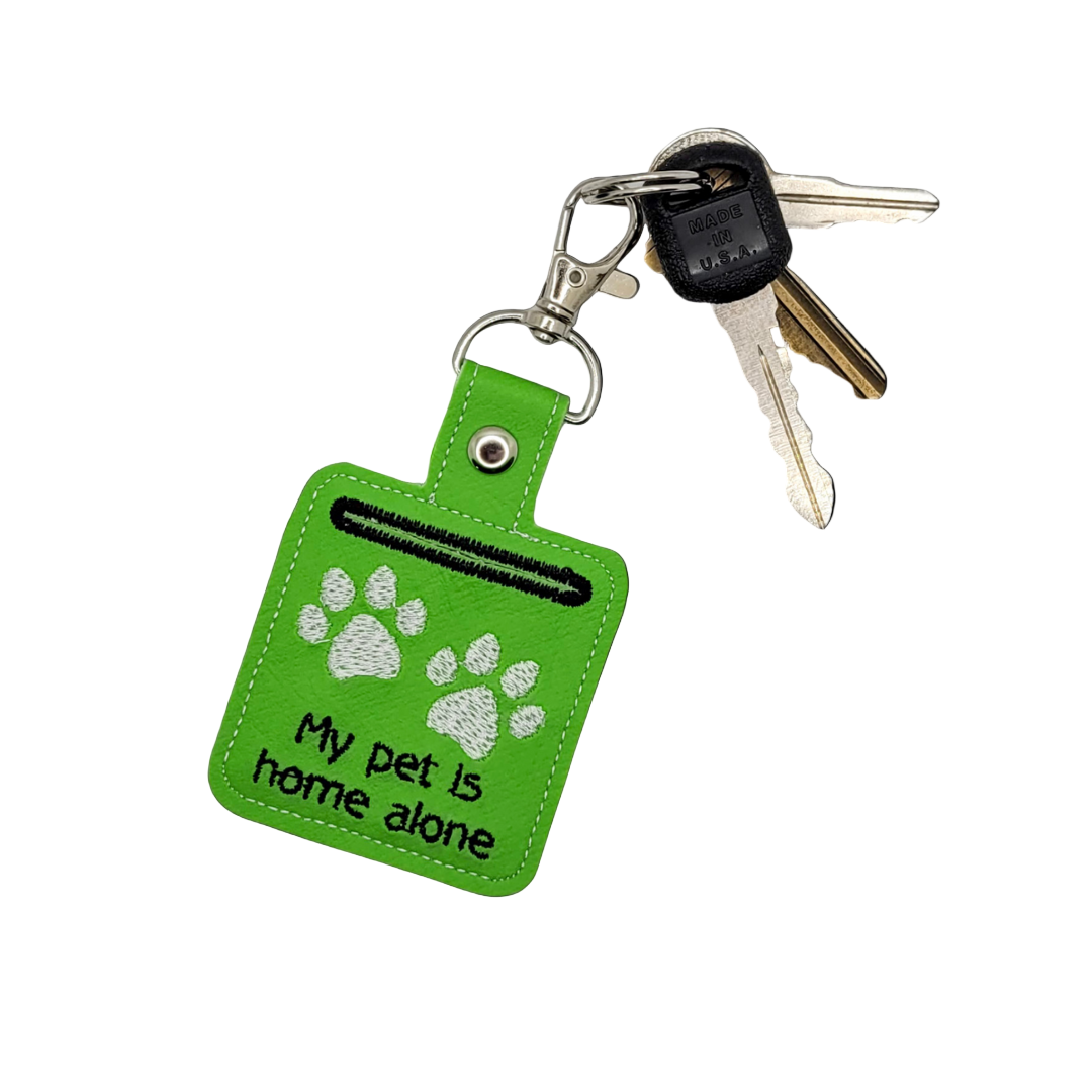 Green keychain with paw prints and text 'My pet is home alone' on a white background