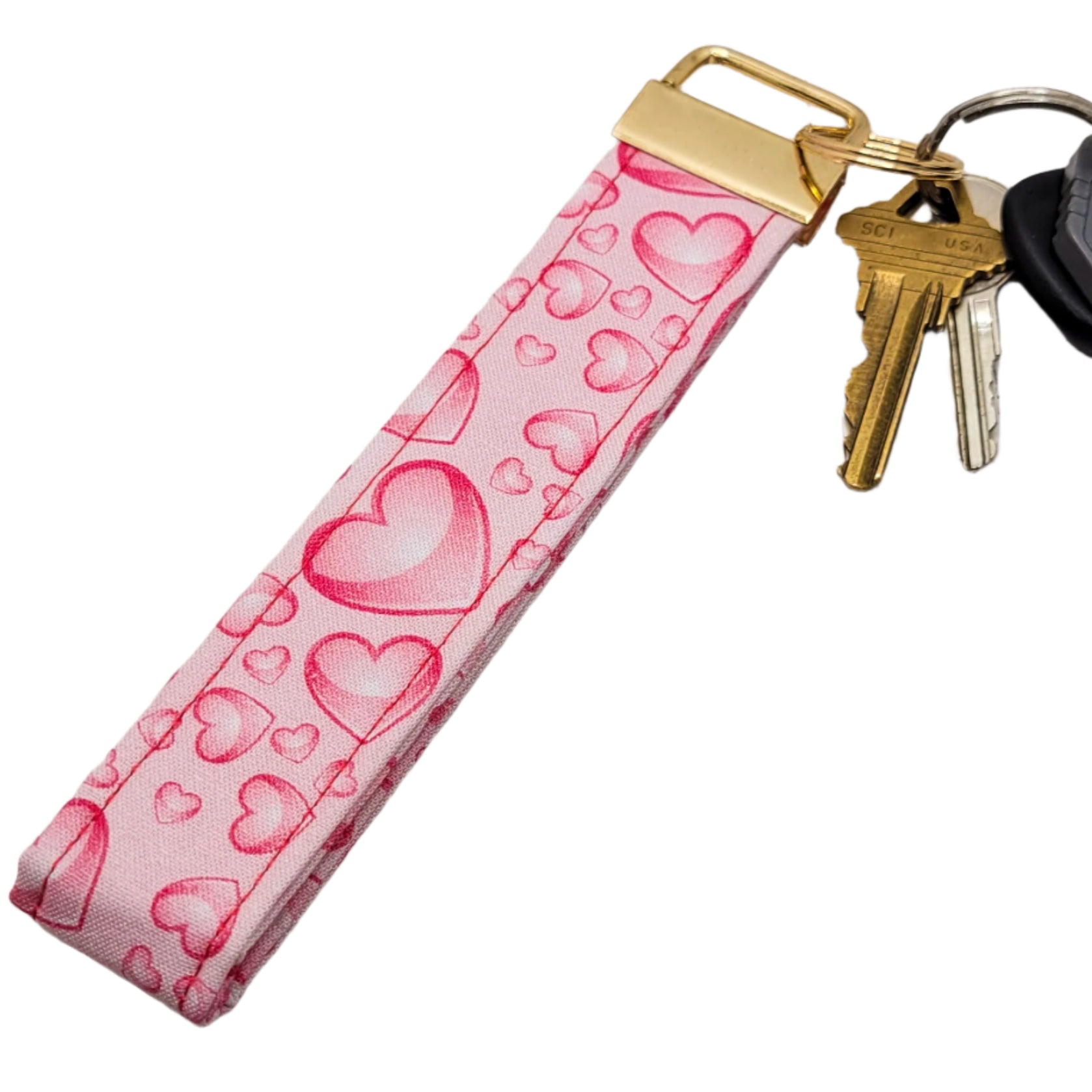 Pink heart-patterned keychain with keys on a white background.