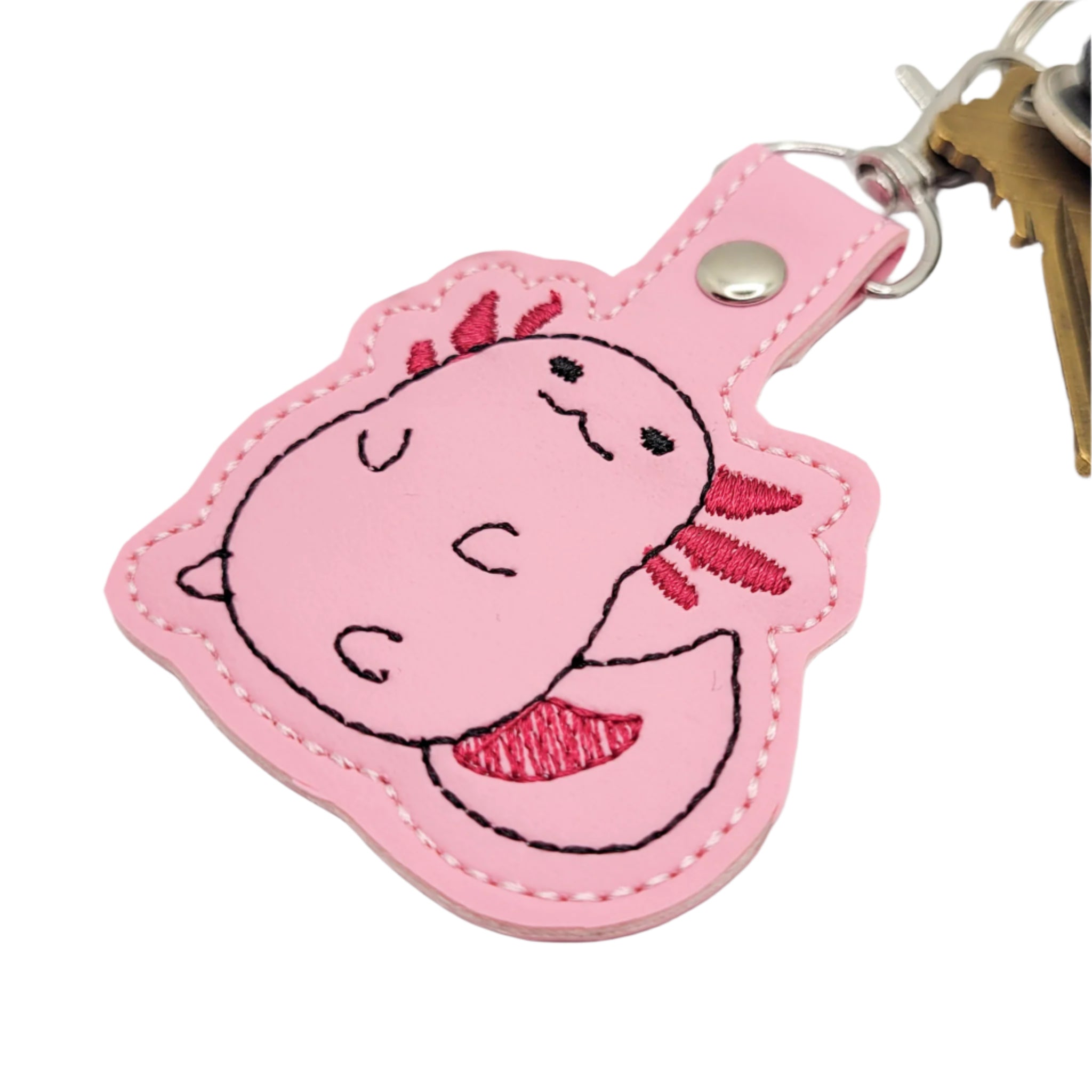 Embroidered vinyl keychain featuring a pink chubby axolotl with dark pink gills, attached to a set of keys