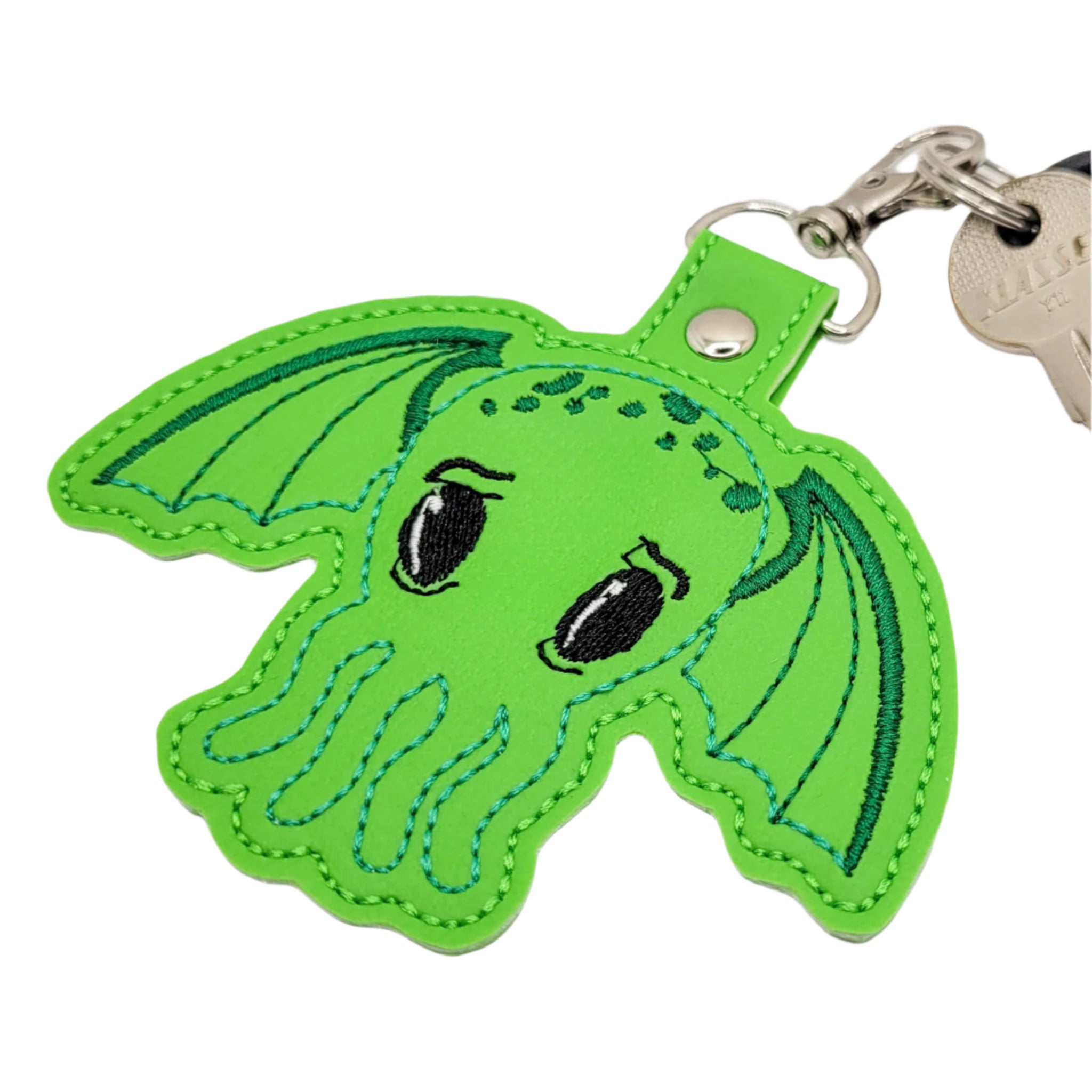 Embroidered vinyl keychain featuring a cute green Cthulhu with large eyes and wings, attached to a set of keys