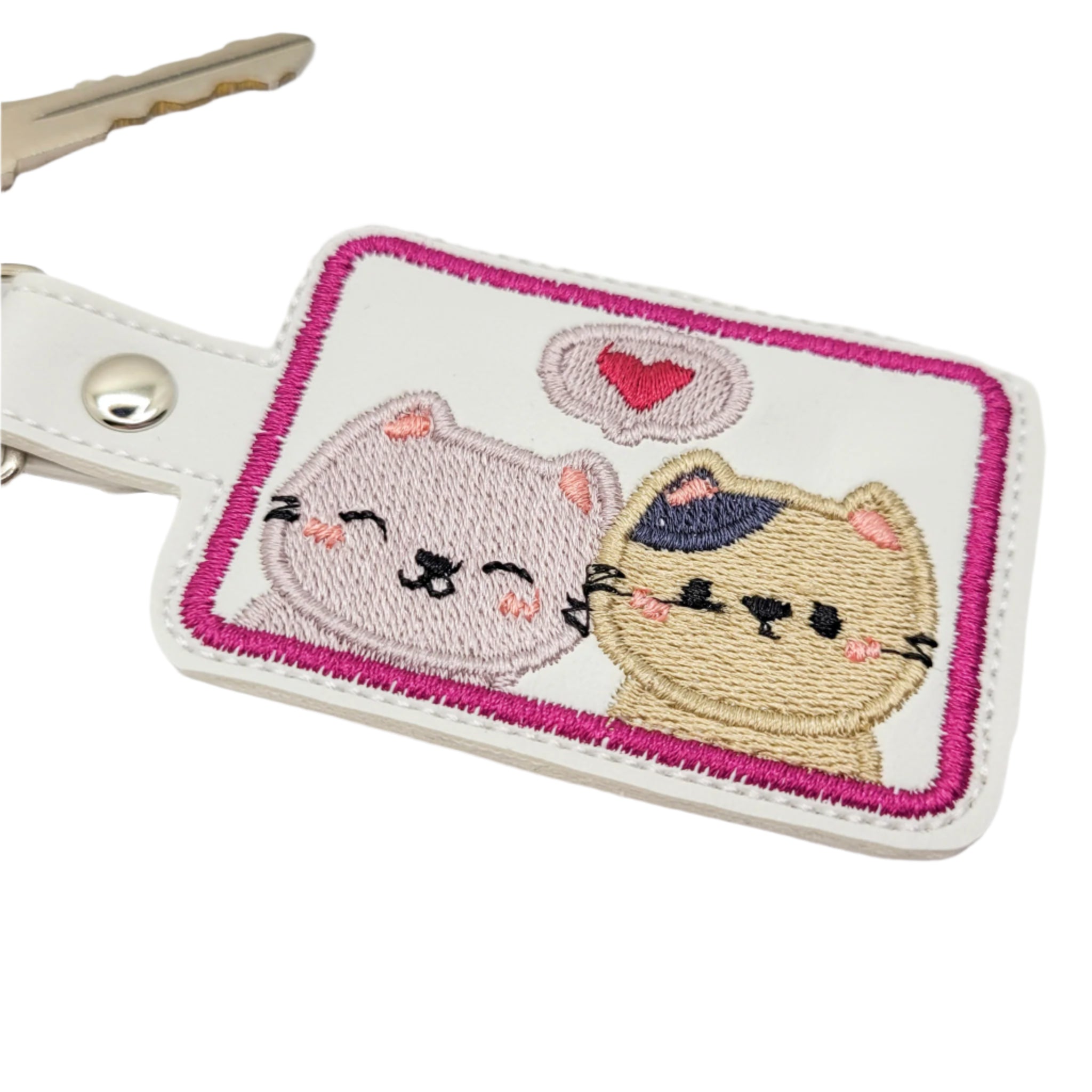 Embroidered keychain with two cats and a heart on a white background