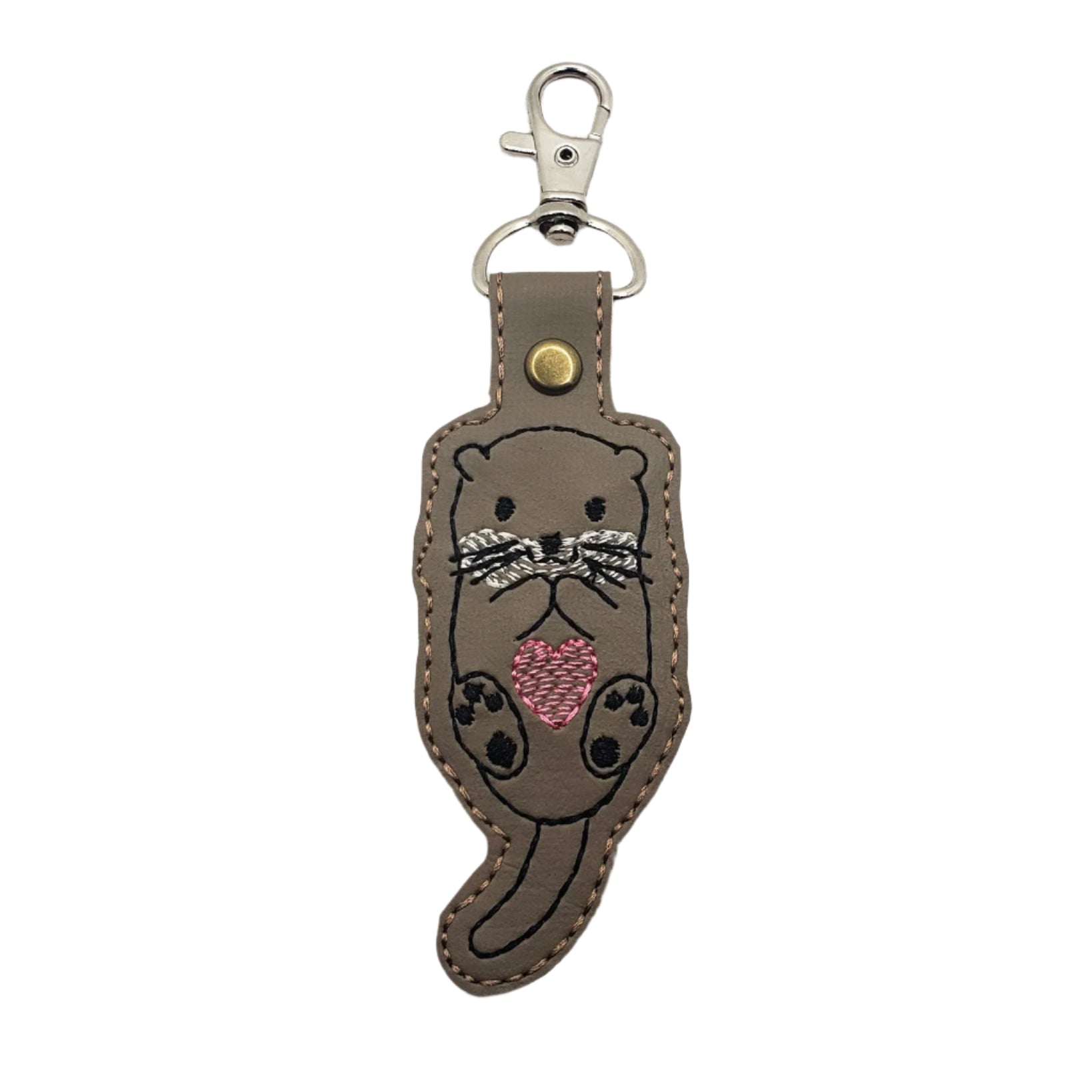 Embroidered vinyl keychain of an otter holding a pink heart, attached to a set of keys.