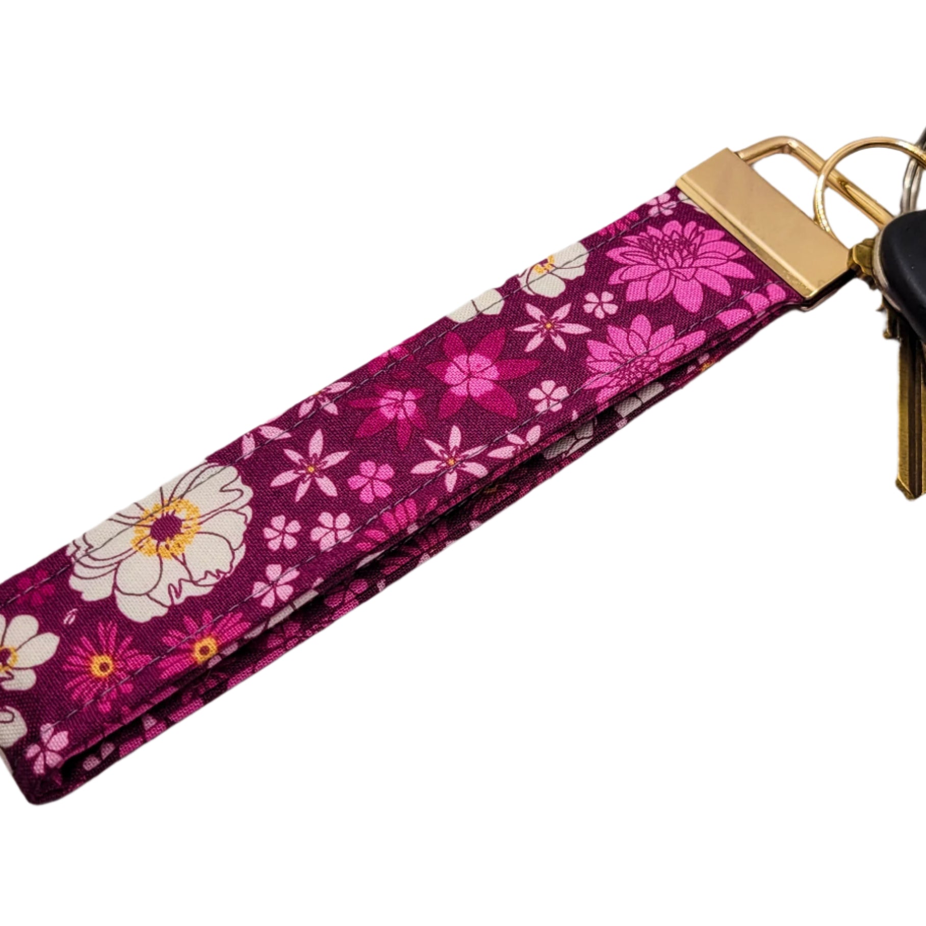 Pink floral keychain attached to keys on a white background.