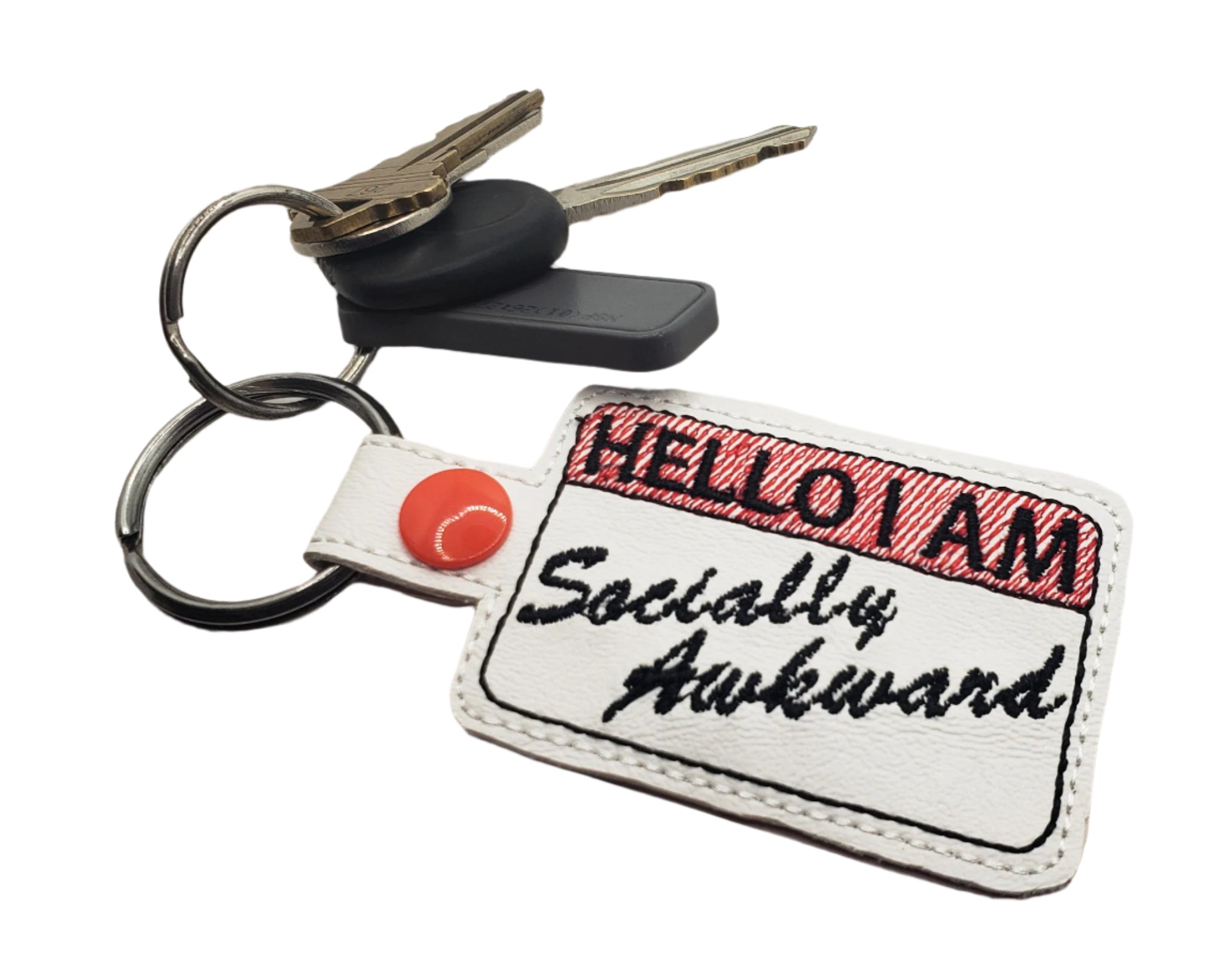Embroidered vinyl keychain with a red-and-white name tag design that reads “Hello I Am Socially Awkward,” shown attached to a set of keys.