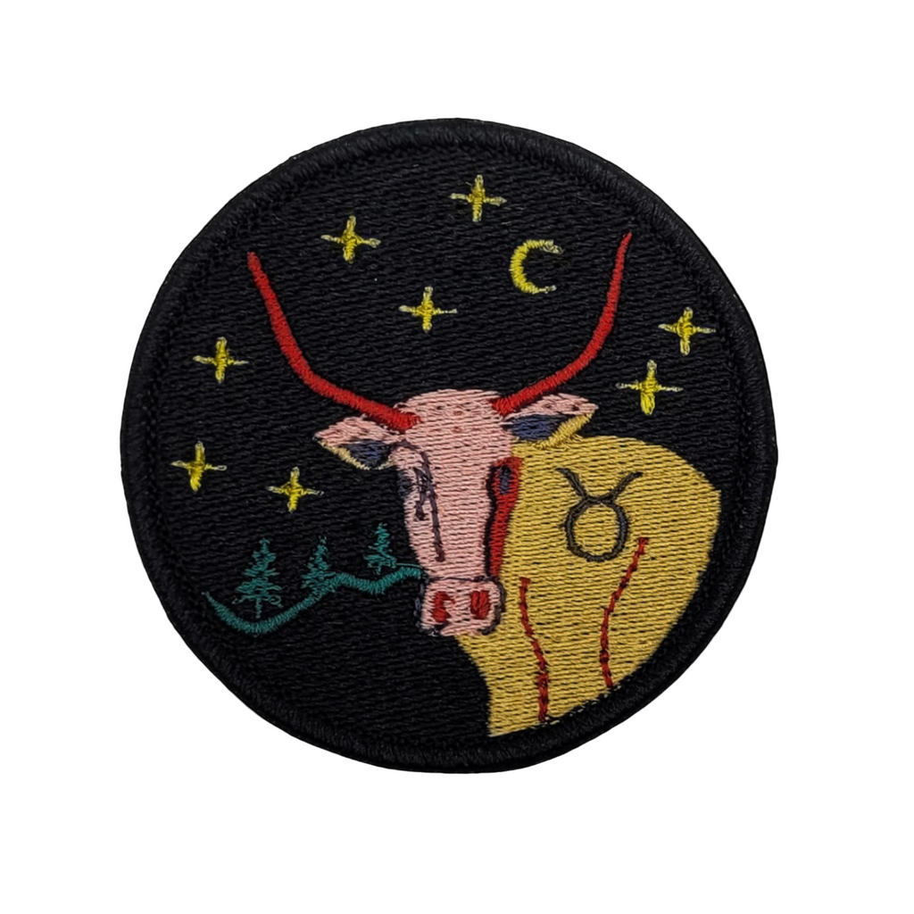 An embroidered patch featuring the Taurus zodiac sign with a bull's head, moon, and stars against a dark background.