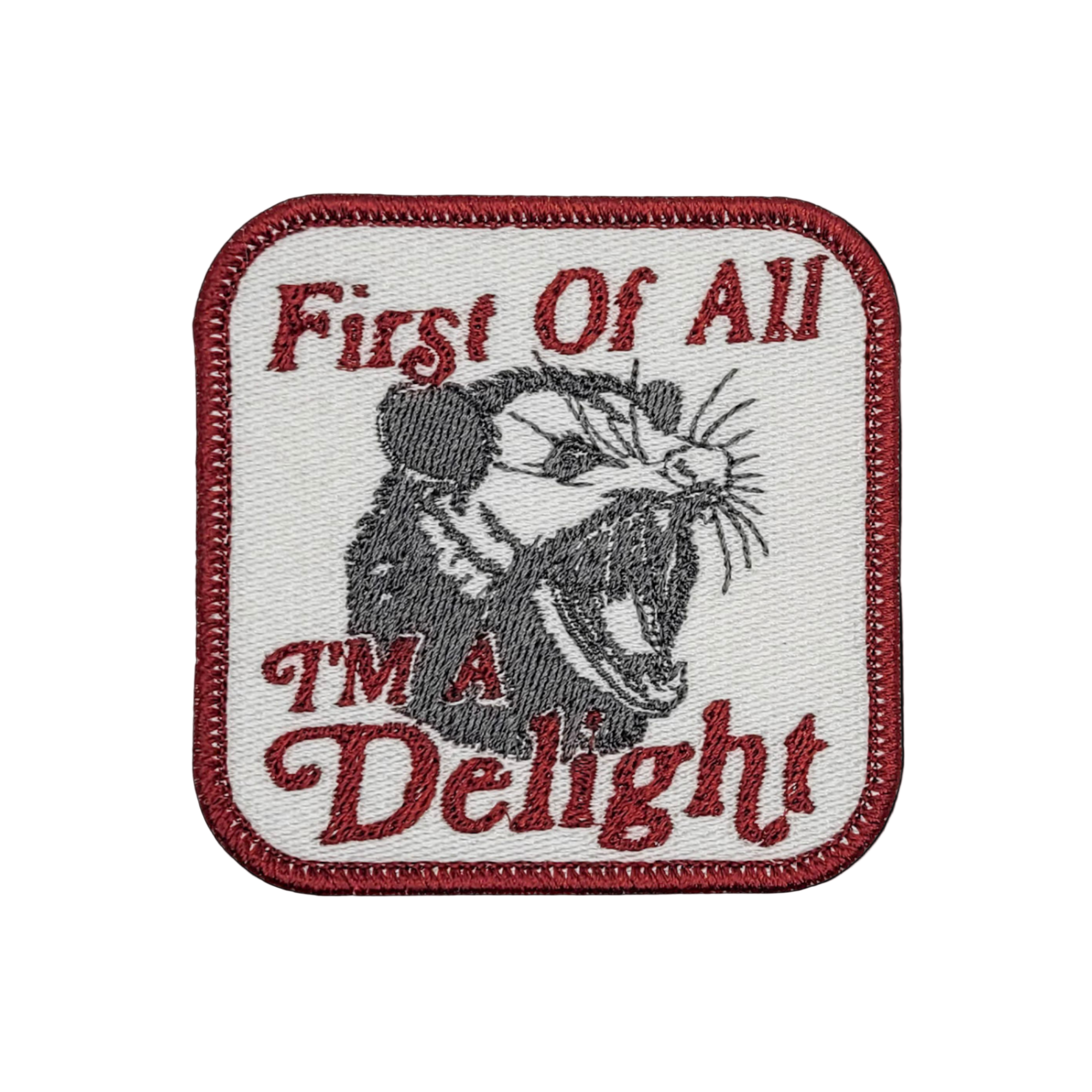 A patch featuring a screaming possum with the text 'FIRST OF ALL, I'M A DELIGHT'.