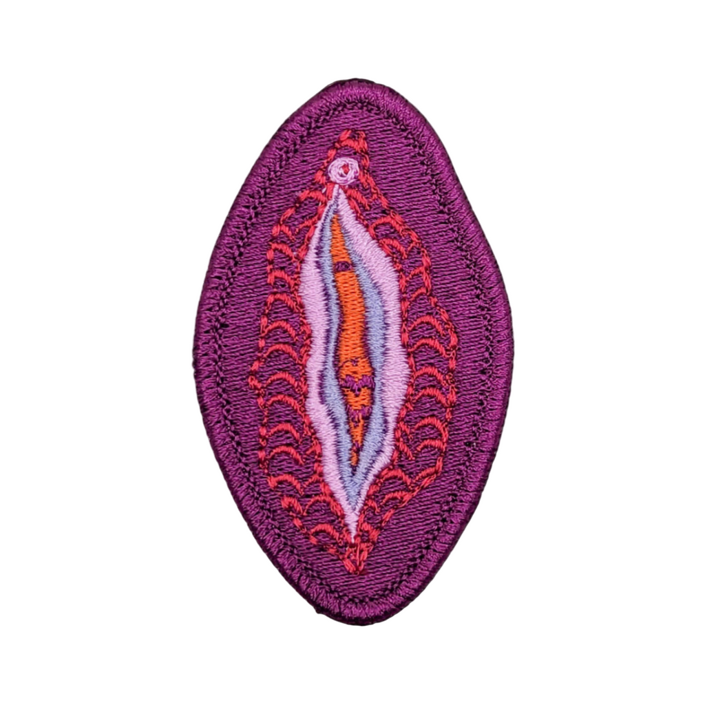 A purple embroidered patch depicting a yoni design, with a vibrant border in red and orange shades.