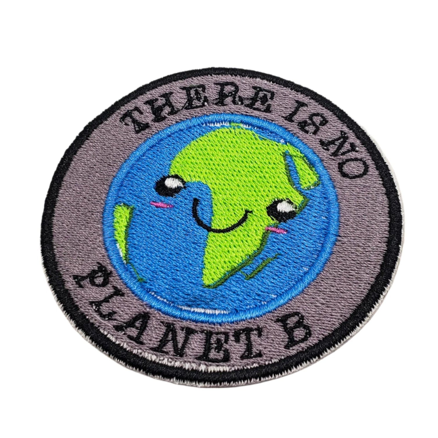 Circular patch with a smiling Earth design and 'There is no Planet B' text on a wooden surface.