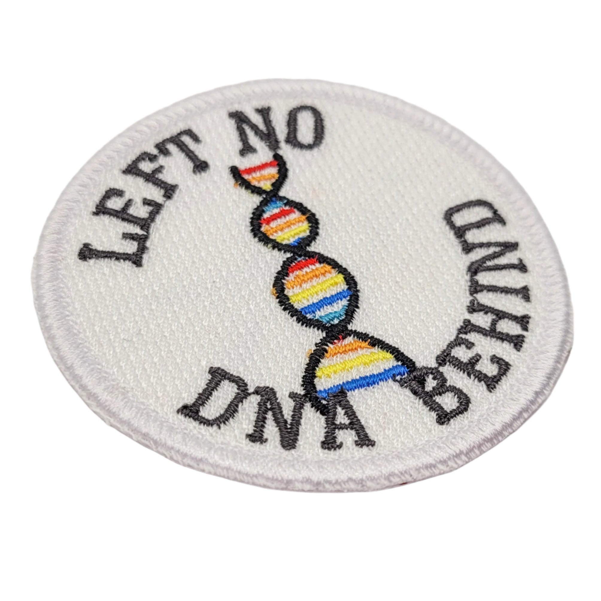 Round patch with rainbow DNA strands and text 'LEFT NO DNA BEHIND' on a white background